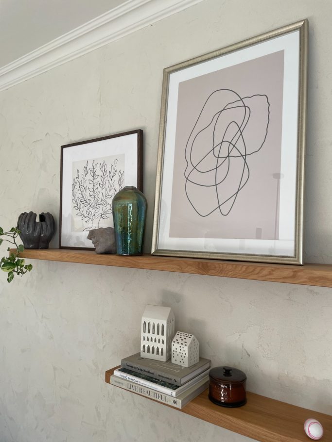 Wohnzimmer einrichten Wandregal mit zwei Bildern, einer Vase, einem Teelicht und einer Pflanze. Wohnzimmer einrichten BonTemps wohnen.