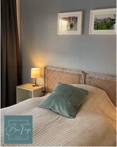 Ein gemütliches Schlafzimmer mit einem Bett und einem Nachttischlampen, hellen Farben und Bildern.