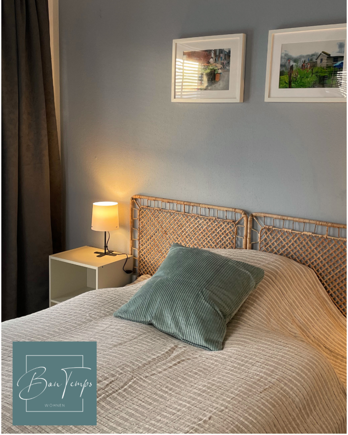 Helles Schlafzimmer mit einem Bett, einem Kissen und einem Nachttisch mit Lampe.