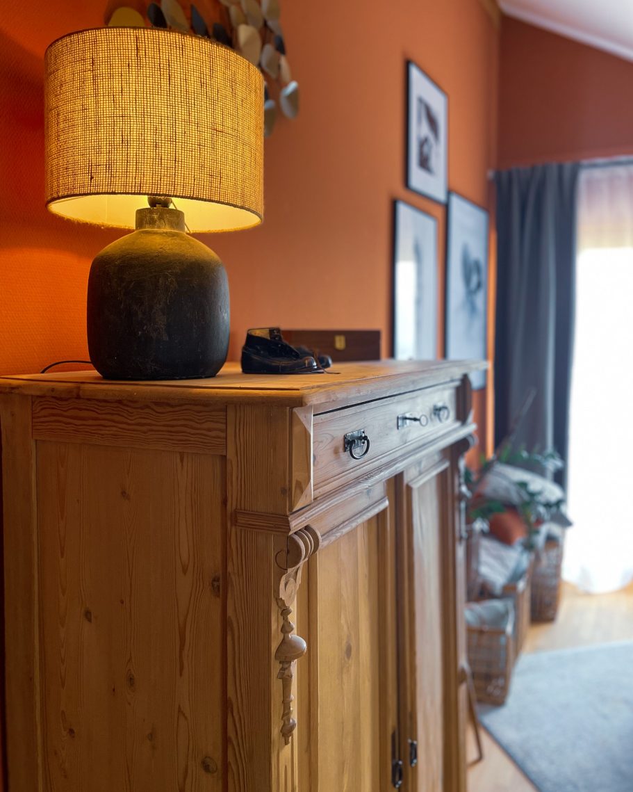 Holztisch mit einer Lampe und einem dekorativen Hintergrund in einem gemütlichen Raum.