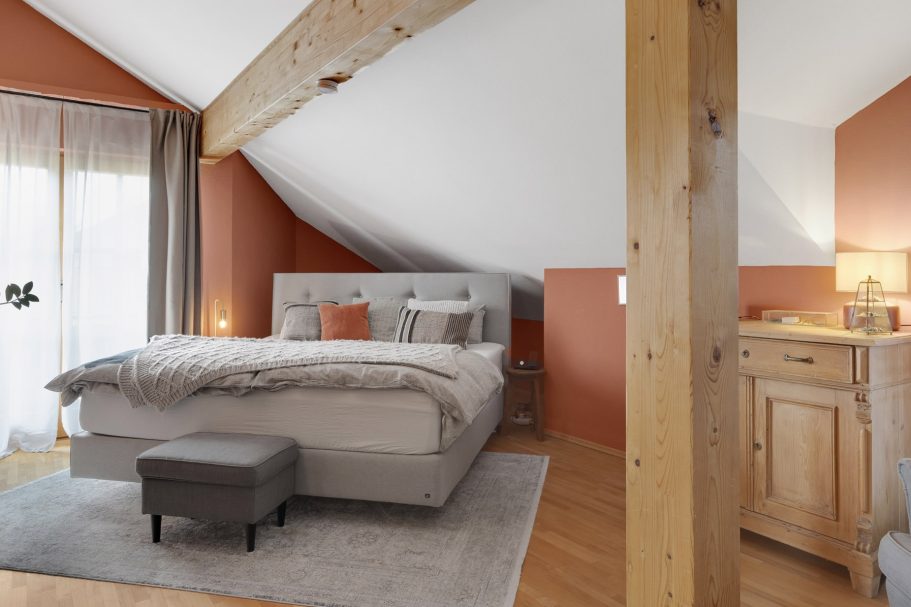 Helle Dachgeschoss-Schlafzimmer mit Holzdetails und gemütlicher Einrichtung.