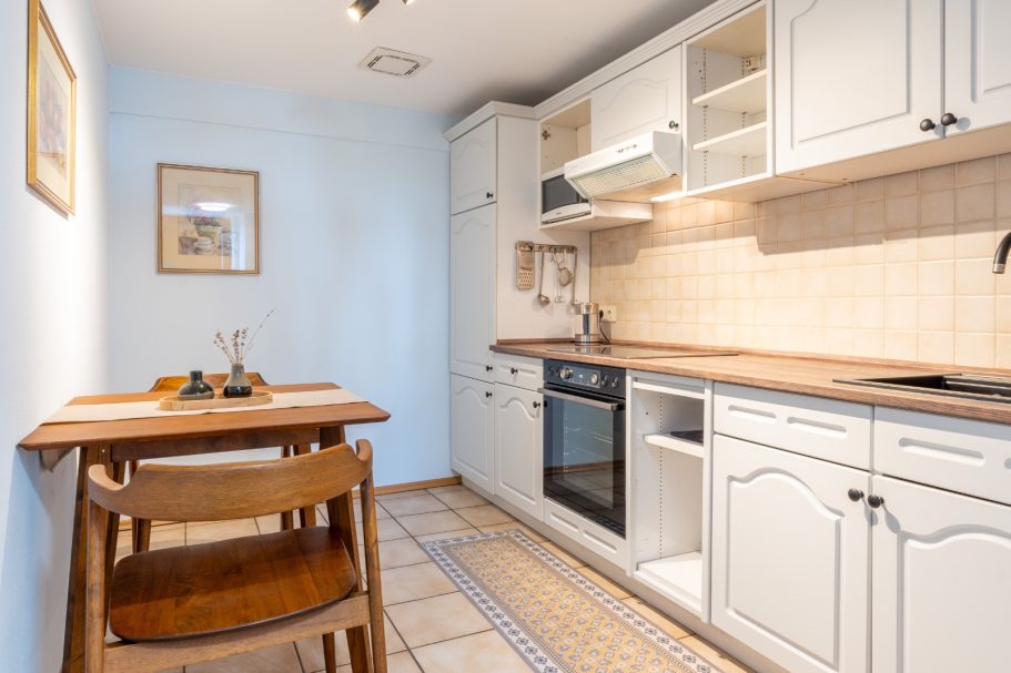Kleine, moderne Küche mit Holzttisch und weißen Möbeln.