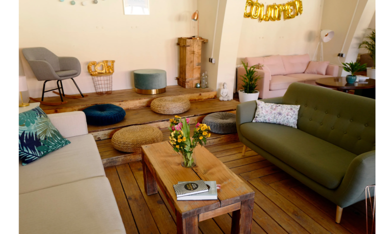Gemütlicher Wohnraum mit Sitzgelegenheiten und einem Holztisch, umgeben von Pflanzen.