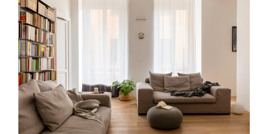 Moderne Wohnküche mit beigem Sofa, Pflanzen und hellen Wänden. Gemütliche Atmosphäre.