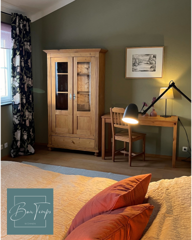 Holzschrank und Schreibtisch mit Lampe in einem Schlafzimmer mit grünem Wandfarbe.