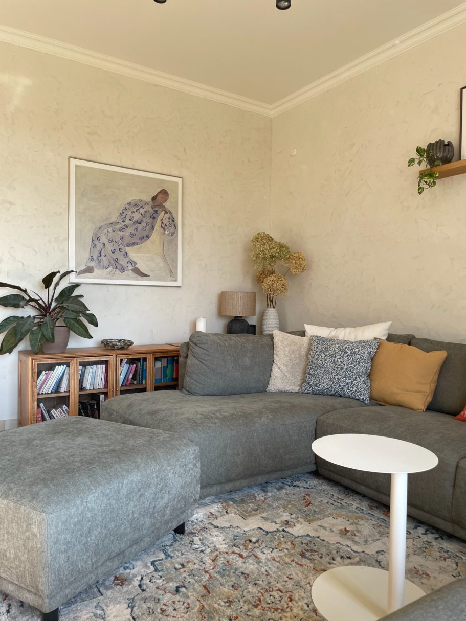 Gemütliches Wohnzimmer mit grauem Sofa, Couchtisch und dekorativen Pflanzen.