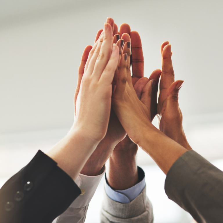 Vereinte Hände in einem High-Five, symbolisieren Teamarbeit und Erfolg.